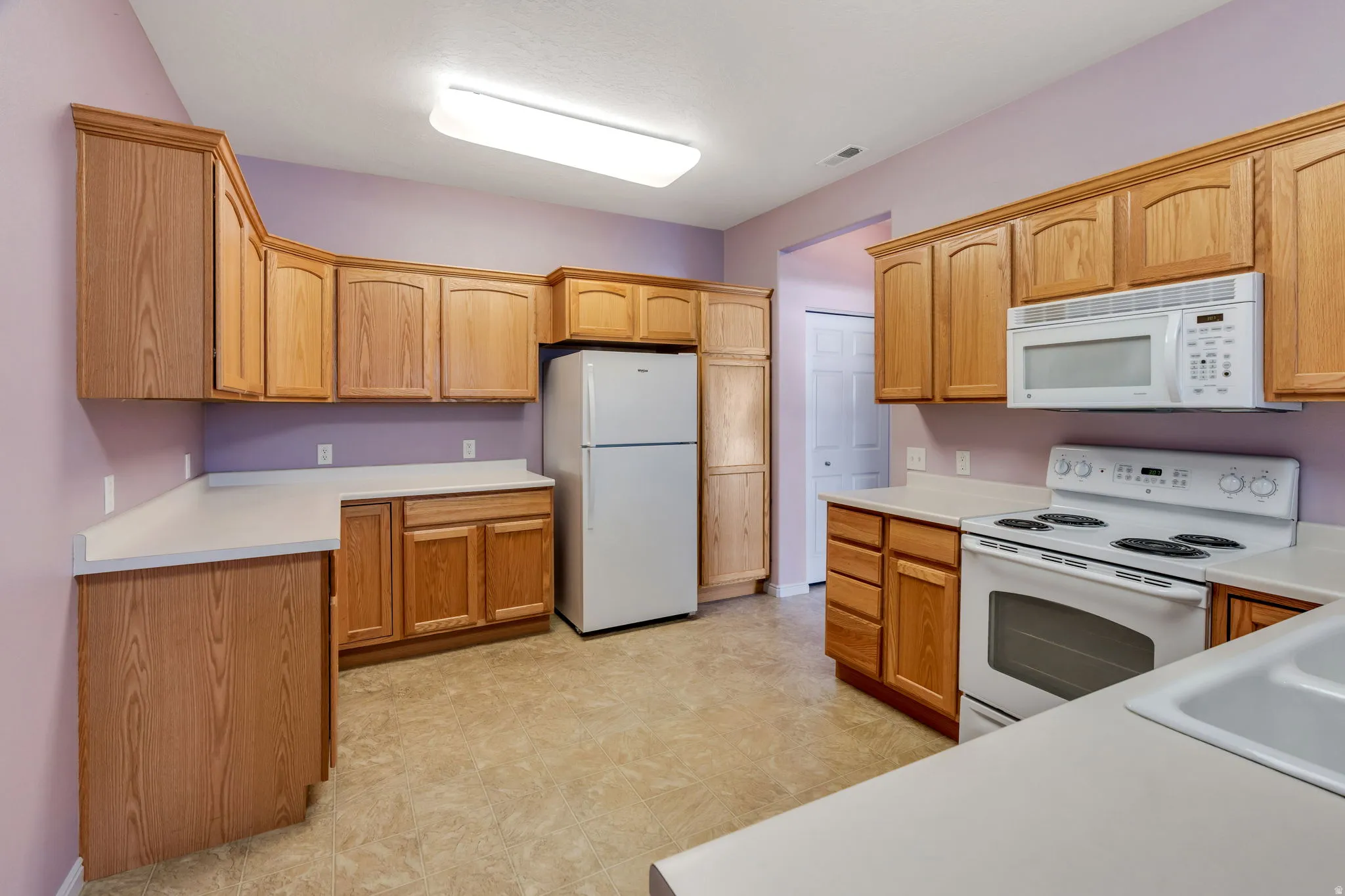 Kitchen featuring wood-finish cabinetry, solid surface countertops, and vinyl flooring
