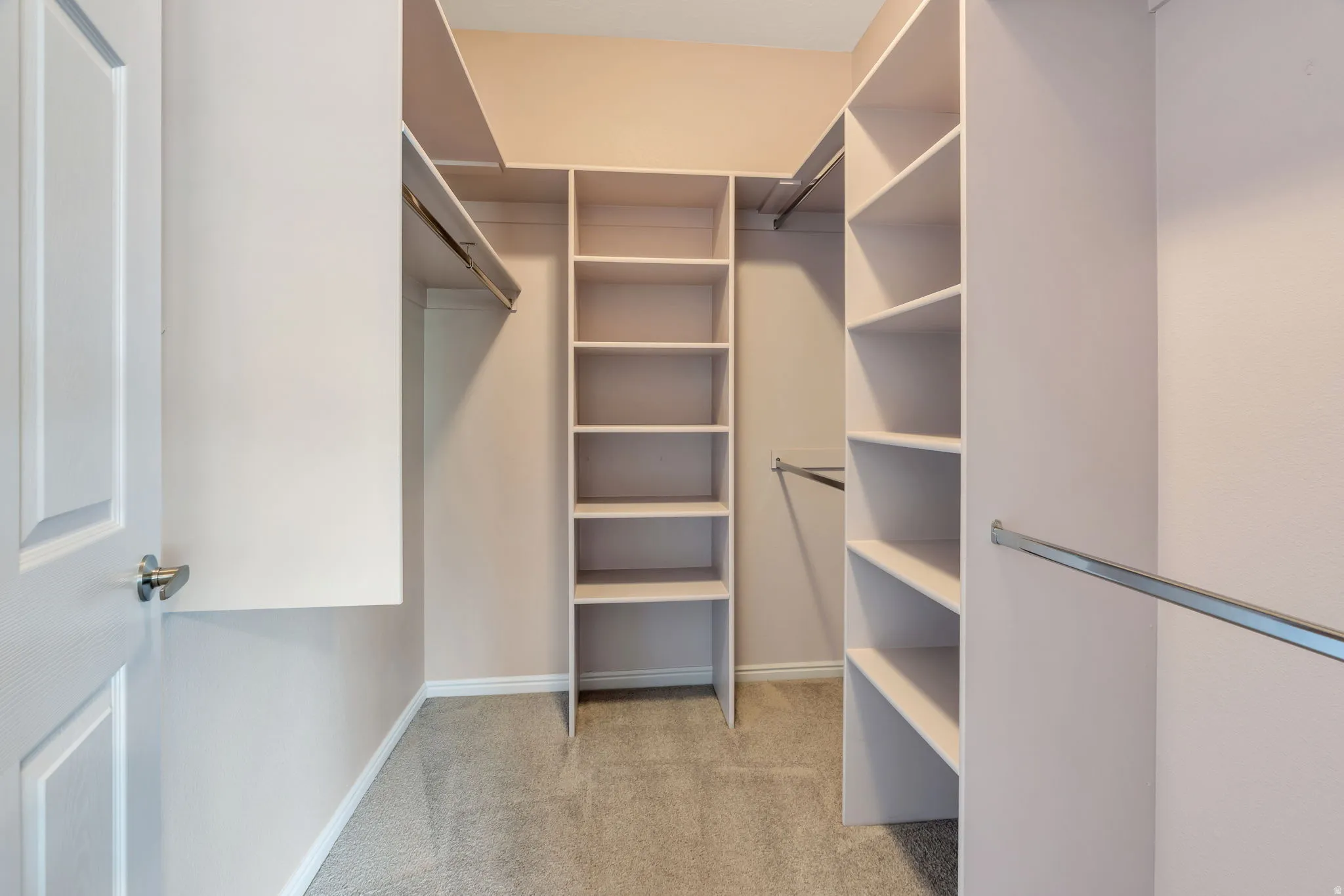 Walk-in closet featuring built-in shelving, multiple hanging rods, and neutral-toned carpeting