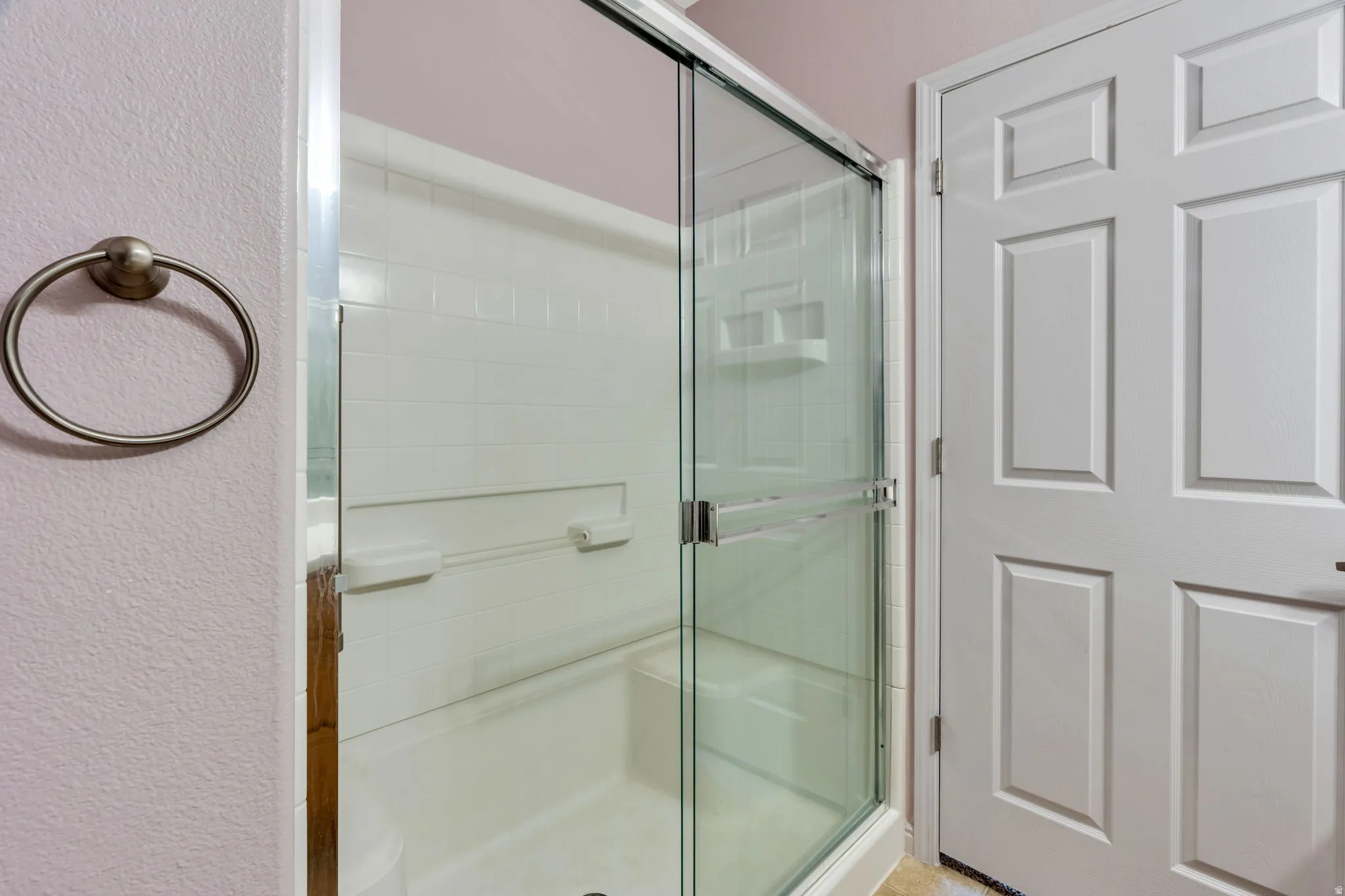 Enclosed shower with clear glass sliding door, integrated shelving, and white subway tile surround