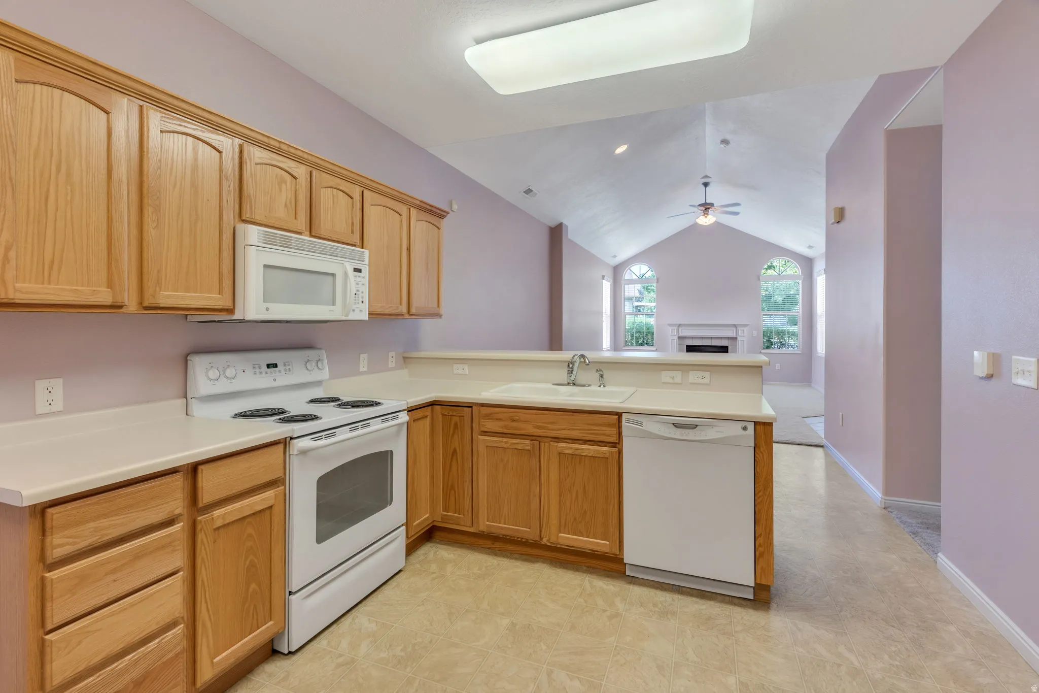 Kitchen featuring wood cabinetry, white appliances, laminate countertops, and a white sink with a chrome faucet