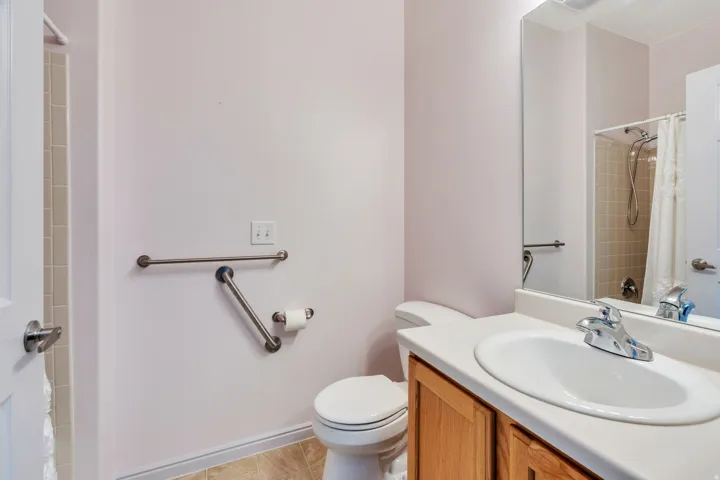 Bathroom featuring a wood-finish vanity with an integrated sink and chrome faucet, a white toilet