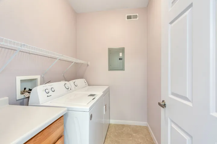 Dedicated laundry area featuring a full-size washer and dryer, wire shelving, a countertop, and wood-finish cabinetry