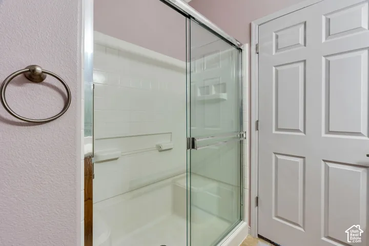 Enclosed shower with clear glass sliding door, integrated shelving, and white subway tile surround
