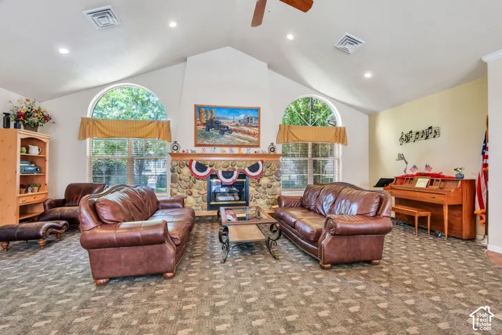 Spacious living area featuring a vaulted ceiling, recessed lighting, and a prominent stone fireplace