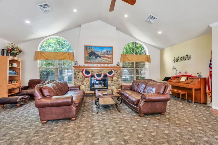 Spacious living area featuring a vaulted ceiling, recessed lighting, and a prominent stone fireplace