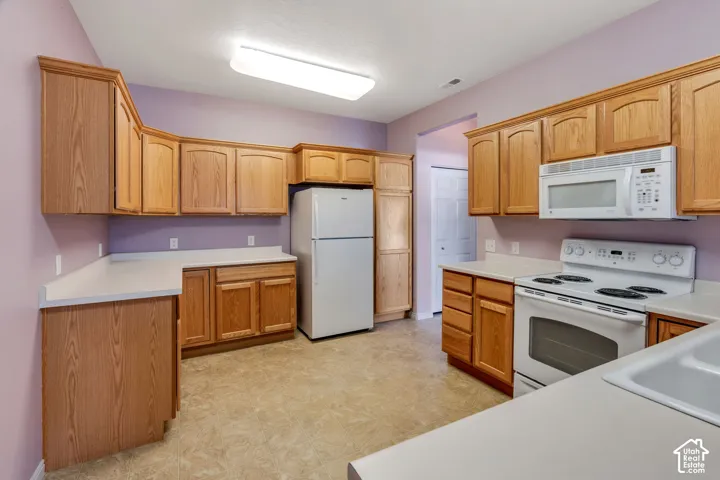 Kitchen featuring wood-finish cabinetry, solid surface countertops, and vinyl flooring