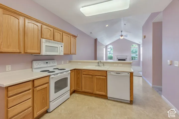 Kitchen featuring wood cabinetry, white appliances, laminate countertops, and a white sink with a chrome faucet