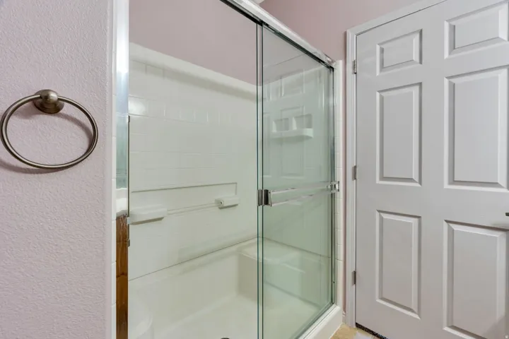 Enclosed shower with clear glass sliding door, integrated shelving, and white subway tile surround