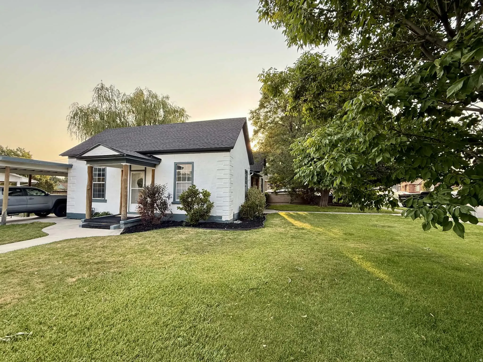 White brick exterior with dark trim and a dark shingle roof