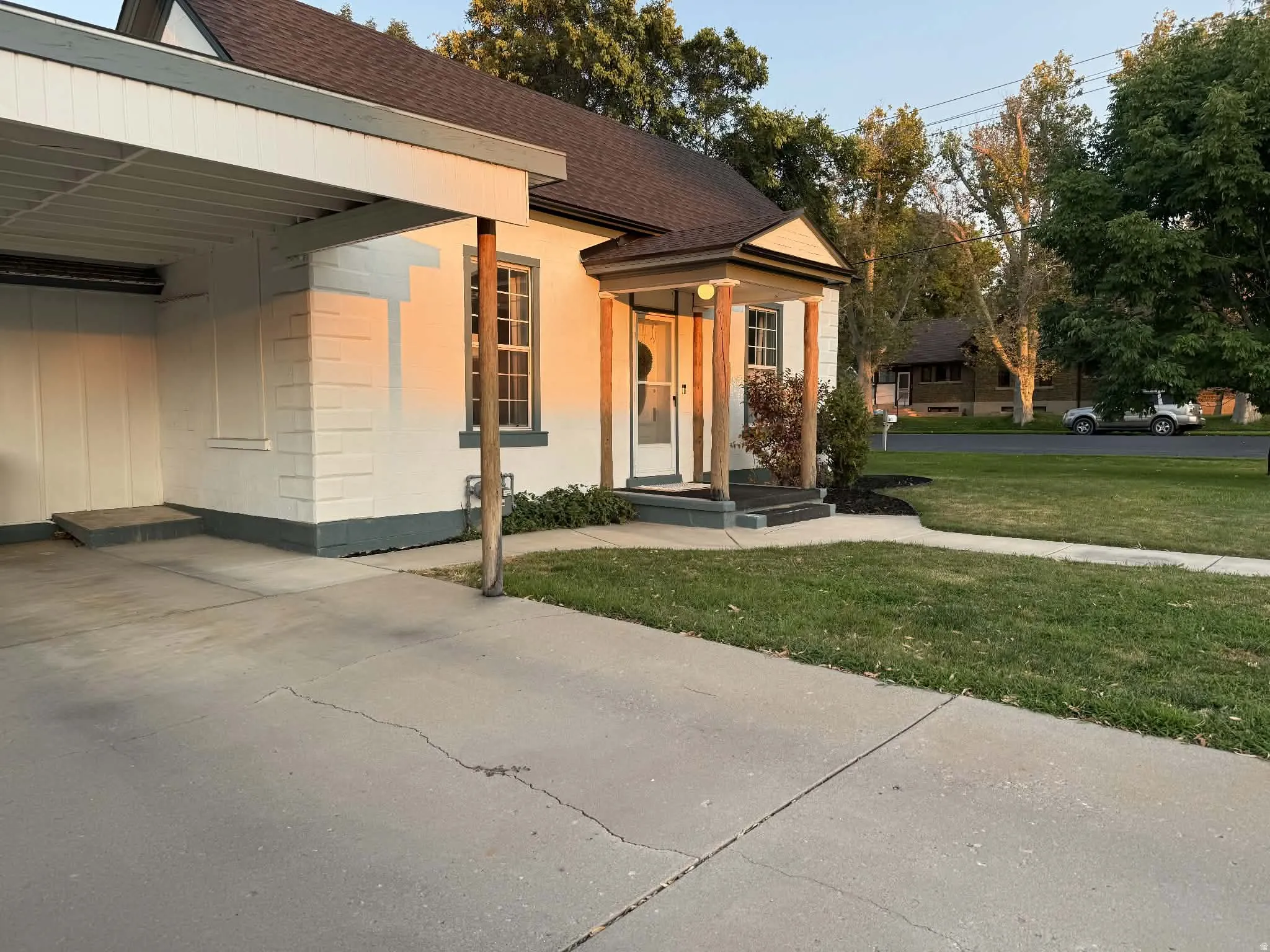 Carport structure with a flat roof, white brick exterior, covered front entry, concrete driveway, and manicured lawn