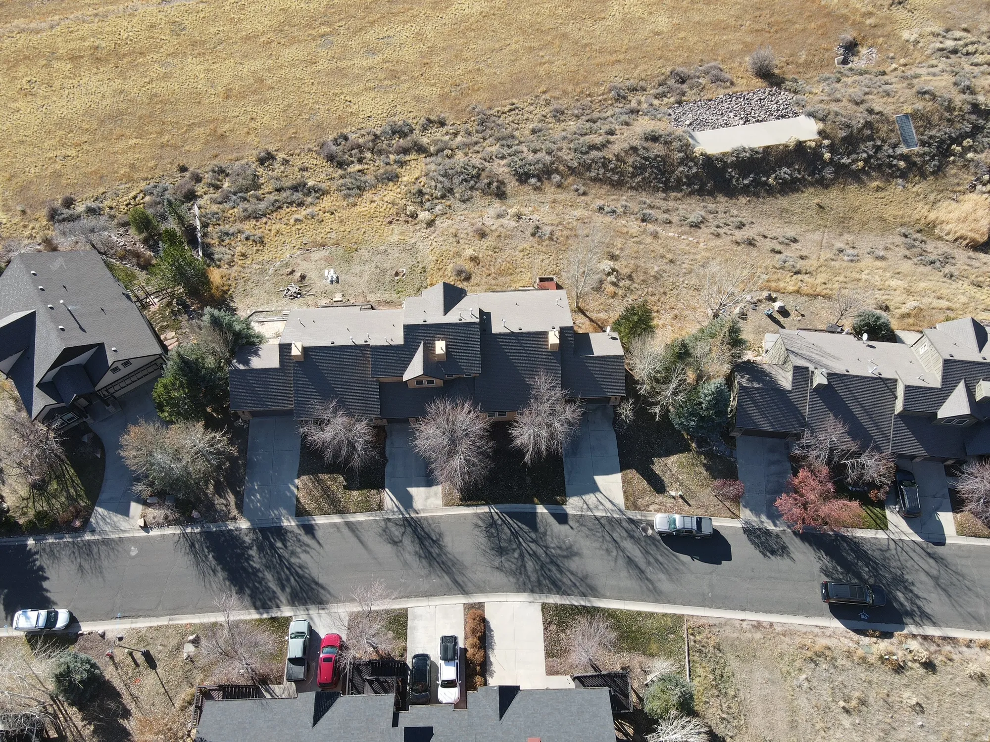 Spacious residential property featuring a multi-gabled roofline, mature landscaping, paved driveway, and an expansive natural landscape backdrop