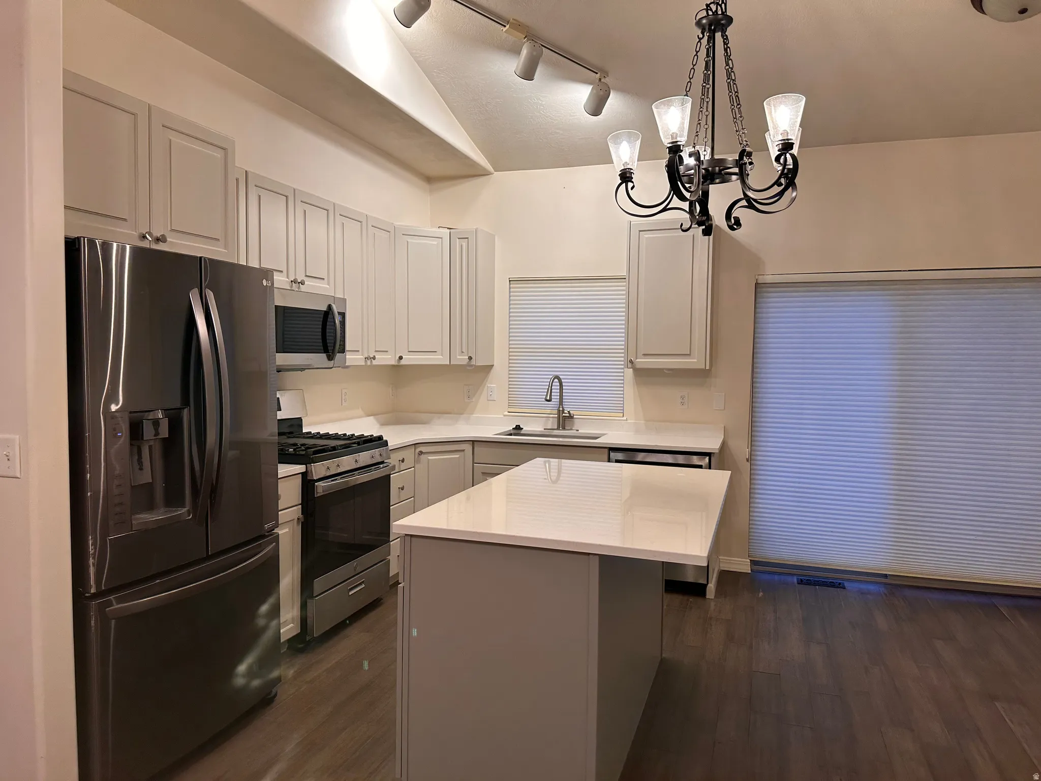 Kitchen featuring white shaker cabinetry, stainless steel appliances, and an island with a white countertop