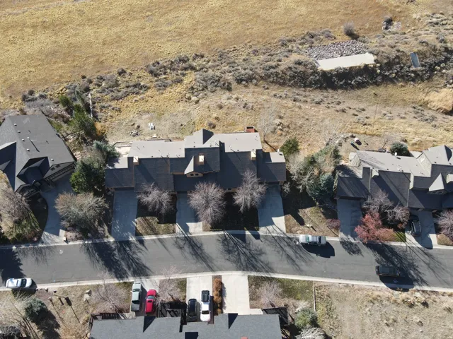 Spacious residential property featuring a multi-gabled roofline, mature landscaping, paved driveway, and an expansive natural landscape backdrop
