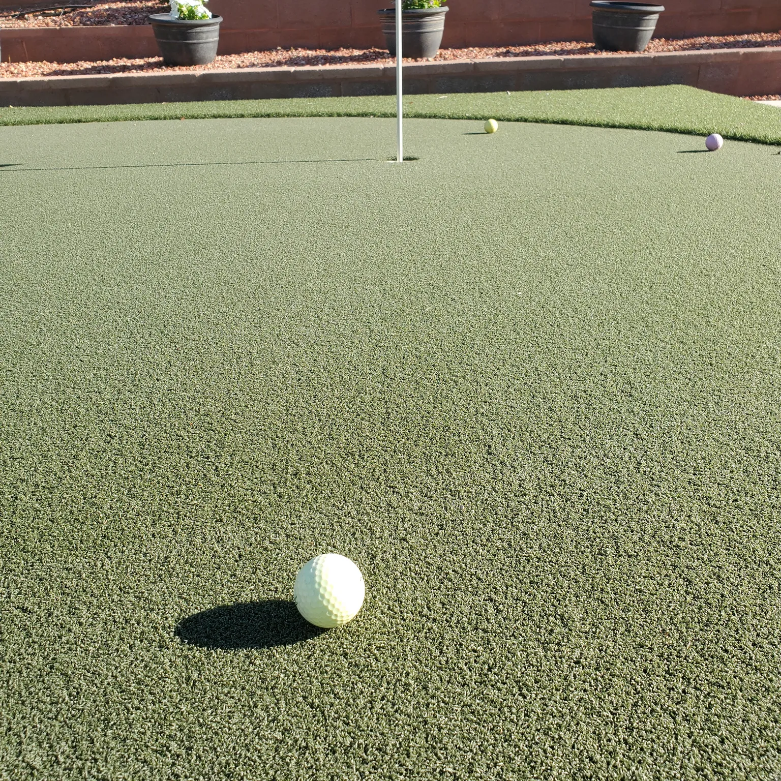 Private putting green featuring artificial turf with multiple holes