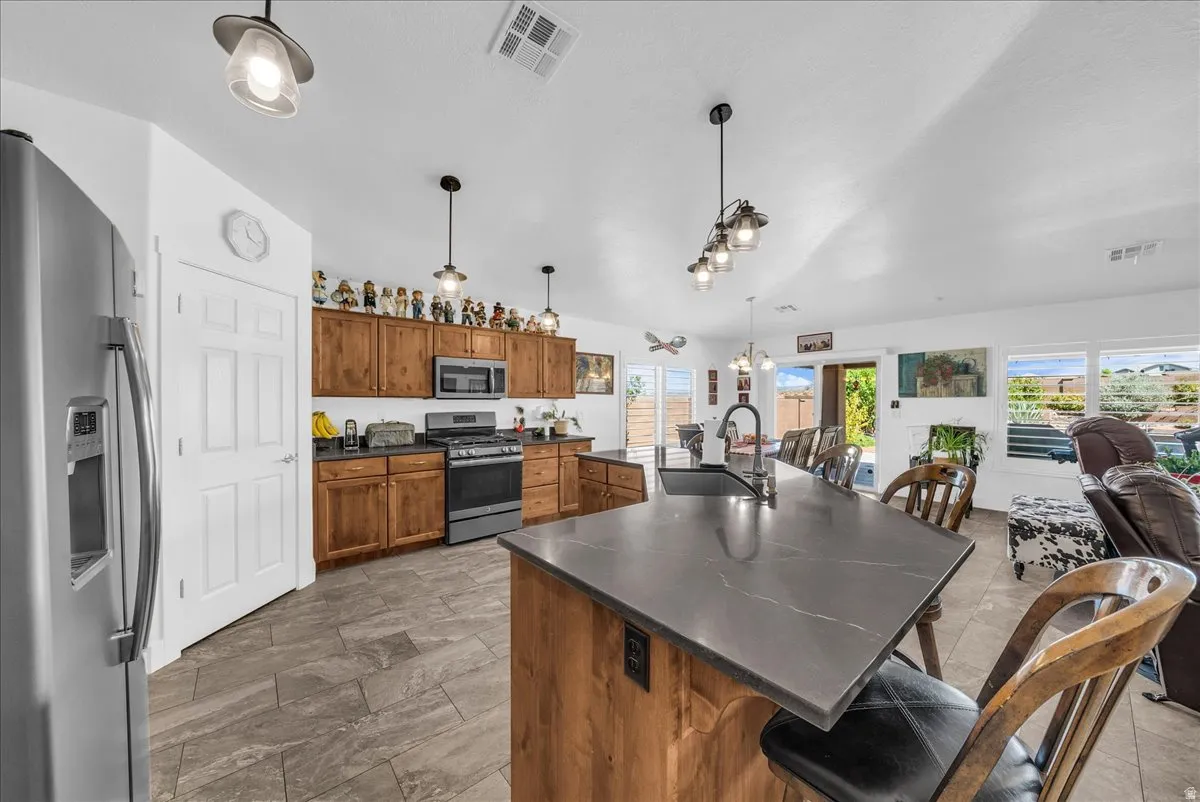 Kitchen featuring an expansive center island with seating, stainless steel appliances, wood-finish cabinetry, and tiled flooring