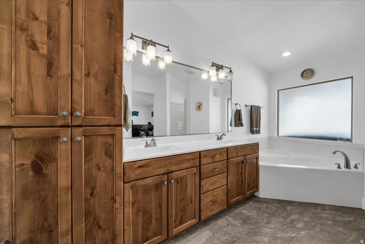 Bathroom featuring dual vanity with wood cabinetry, white countertops, and integrated sinks