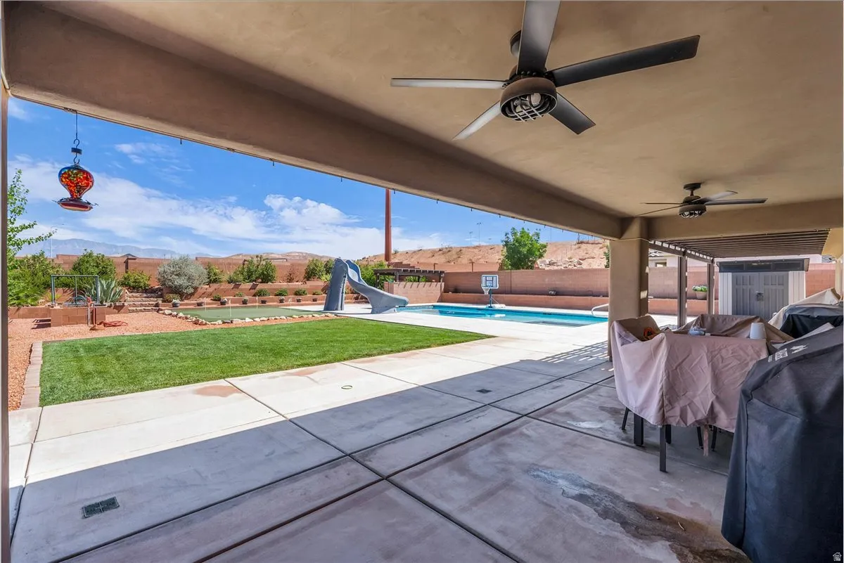 Covered patio area featuring overhead ceiling fans and concrete flooring