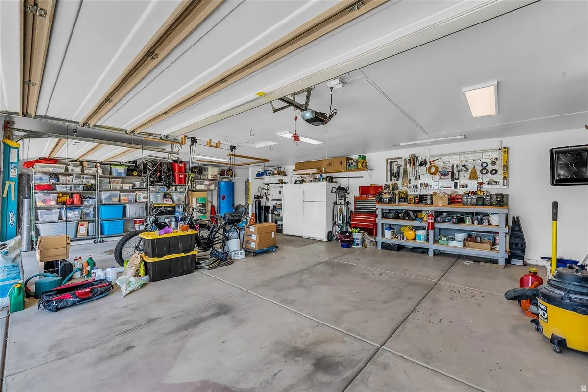 Spacious garage with concrete flooring, overhead lighting, and abundant built-in shelving