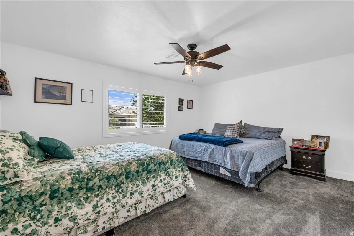 White walls, gray carpet flooring, and a ceiling fan with integrated lighting
