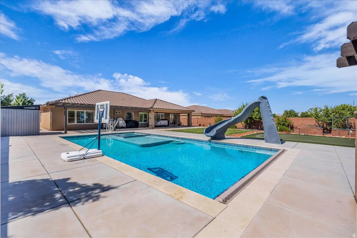 Expansive backyard featuring a rectangular in-ground swimming pool, integrated spa, and a pool slide