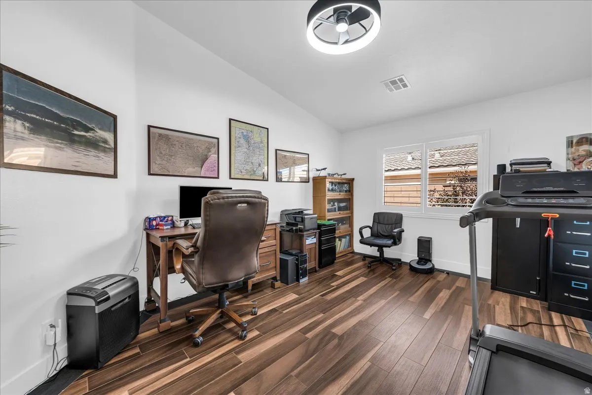 Spacious interior room featuring wood-finish flooring, white walls, and a recessed window with white blinds