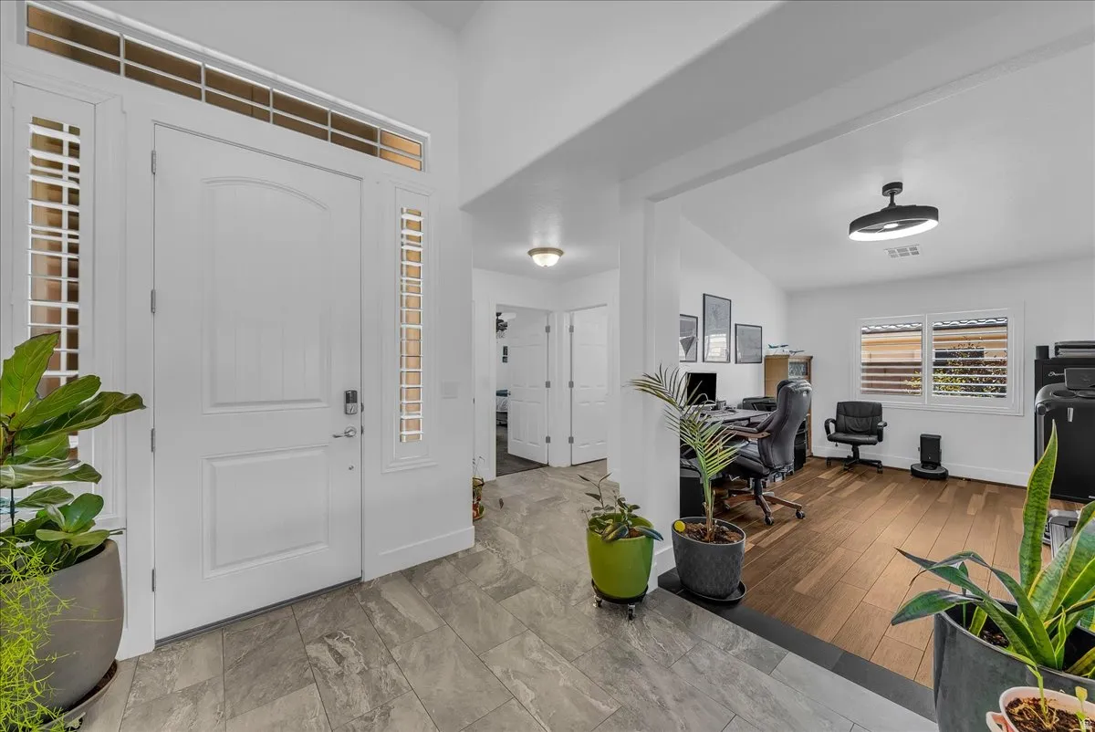 Entryway featuring gray tile flooring, a white arched panel door, and sidelight windows with a transom