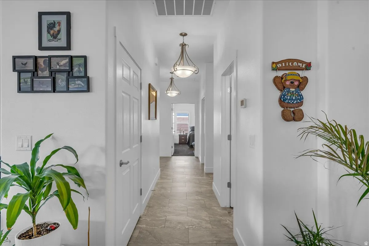 Hallway featuring tile flooring, white interior doors, and overhead light fixtures