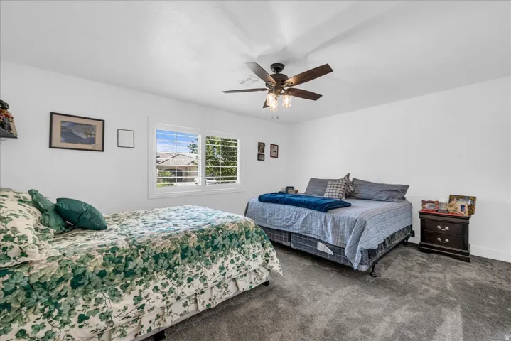 White walls, gray carpet flooring, and a ceiling fan with integrated lighting