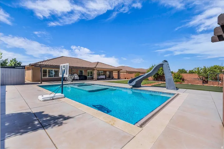 Expansive backyard featuring a rectangular in-ground swimming pool, integrated spa, and a pool slide