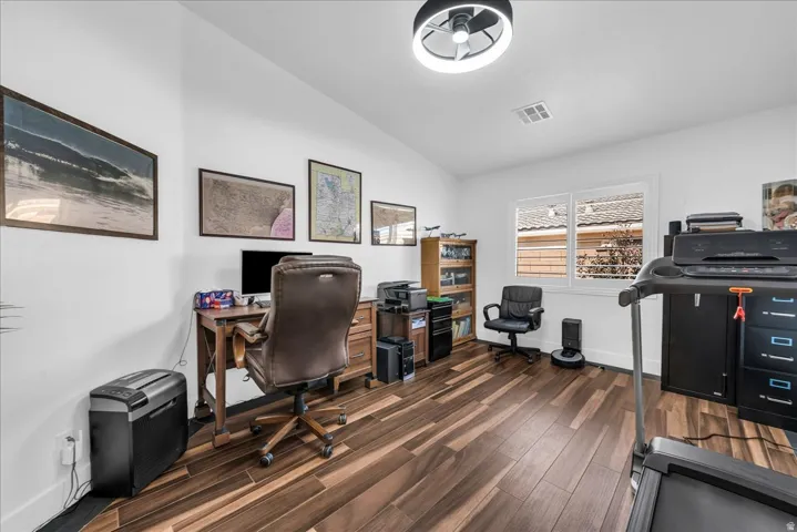 Spacious interior room featuring wood-finish flooring, white walls, and a recessed window with white blinds