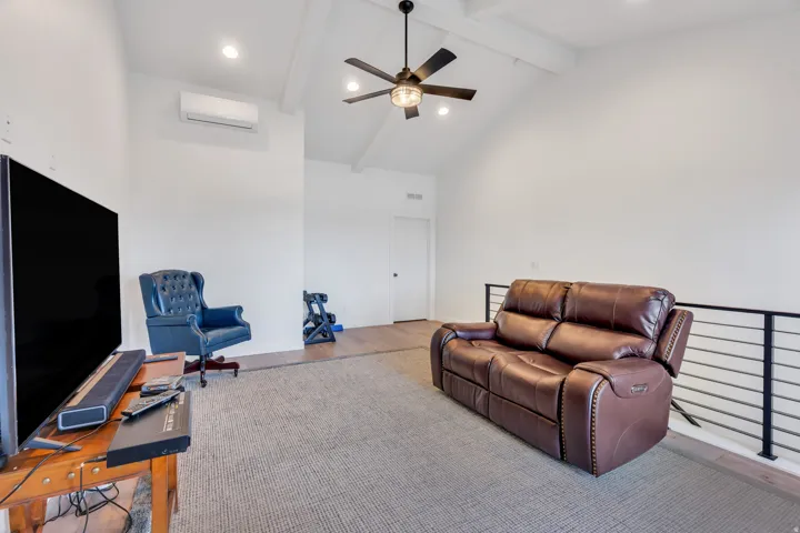 Loft space featuring a vaulted ceiling with exposed beams, wood-finish flooring, recessed lighting, ceiling fan, and a contemporary railing