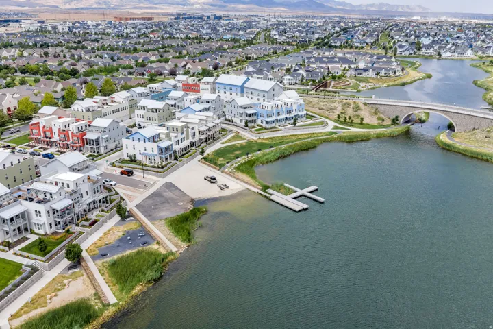 Waterfront community featuring a boat launch, two floating docks, a stone arch bridge, and a variety of multi-story residences