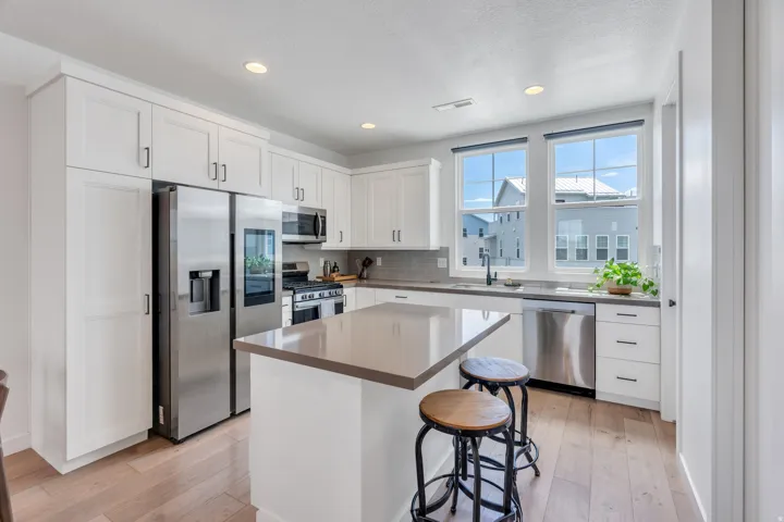 Modern kitchen featuring white shaker cabinetry, stainless steel appliances, a center island with countertop seating, and light wood-finish flooring
