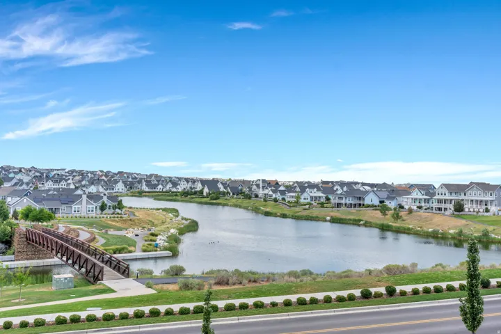 Expansive community lake featuring a pedestrian bridge and surrounding residences