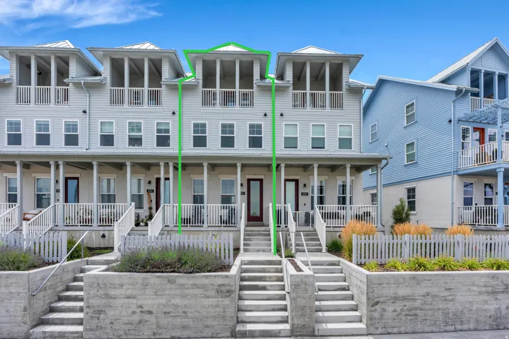 Three-story townhouse with a light gray siding exterior, featuring a covered front porch, a second-story balcony, and a third-story screened-in porch
