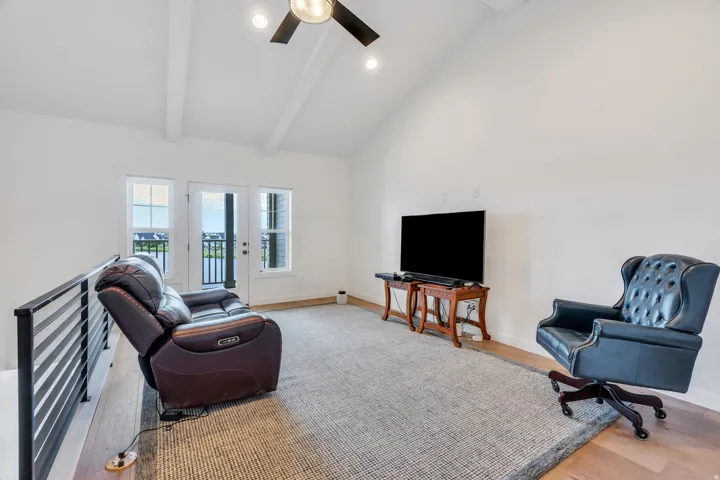 Vaulted ceiling with exposed beams and a ceiling fan