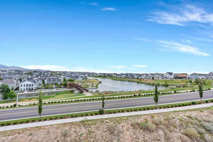 Expansive residential community featuring a prominent lake and a variety of housing styles, with mountain backdrops, green spaces, and a pedestrian bridge