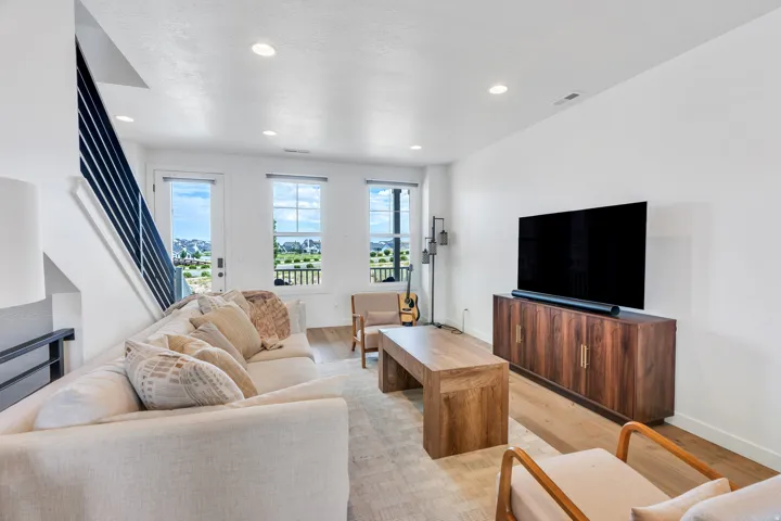 Living area featuring light wood-finish flooring, recessed lighting, and a white color palette