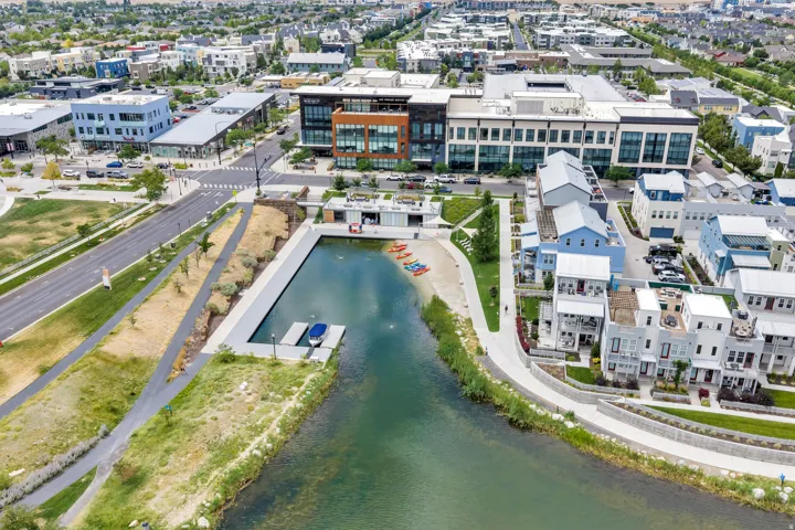 Waterfront community featuring modern residential architecture, commercial properties, a paved pedestrian pathway, and a private dock with boat access