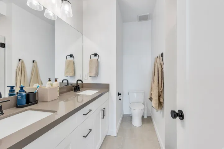 Spacious bathroom featuring a dual vanity with light gray countertops, white cabinetry, and matte black hardware