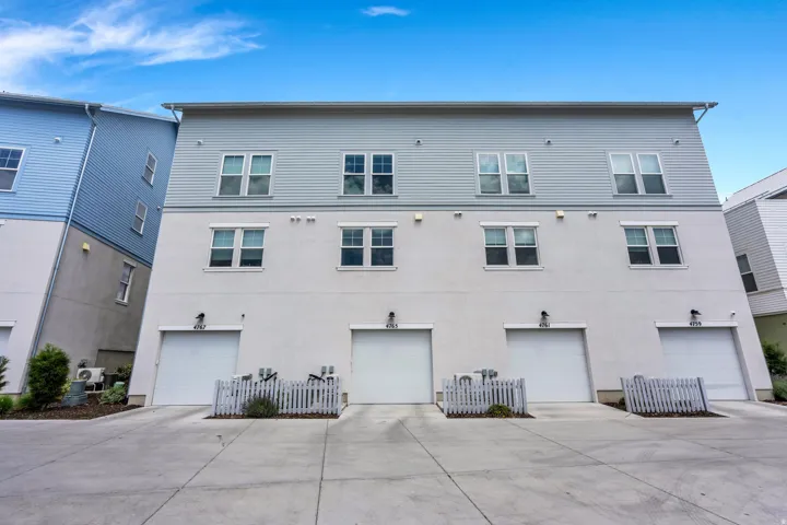 Multi-level townhome exterior featuring light blue siding, stucco finish, and multiple windows