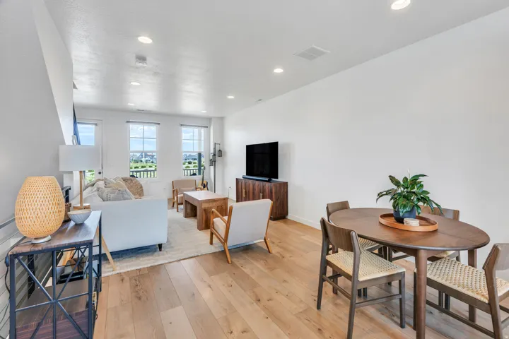 Open-concept living area featuring wood-finish flooring, recessed lighting, and multiple windows
