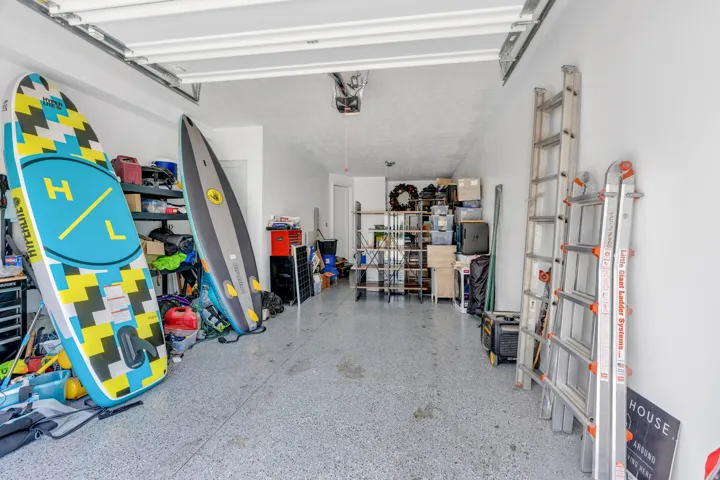 Spacious garage featuring a durable epoxy floor coating, white painted walls, and an automatic garage door opener