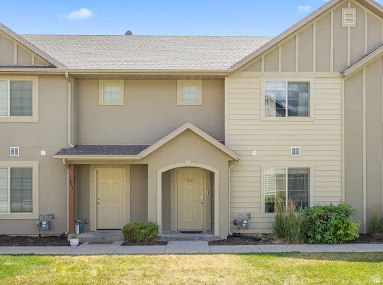 Exterior featuring a neutral-toned stucco and siding facade, covered entryways, and multiple windows