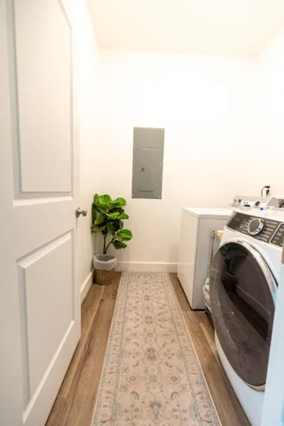 Dedicated laundry space featuring wood-finish flooring, white baseboards, and a neutral wall color