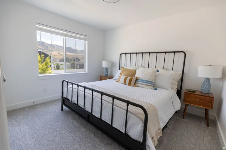 Bright room featuring a large window, neutral wall paint, patterned carpeting, white baseboards, and a ceiling-mounted light fixture