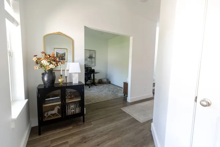 Entryway featuring wood-finish flooring, white baseboards, and a framed archway leading to an additional room