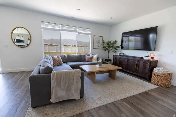 Spacious living area featuring expansive windows with mountain scenery, wood-finish flooring, and white walls