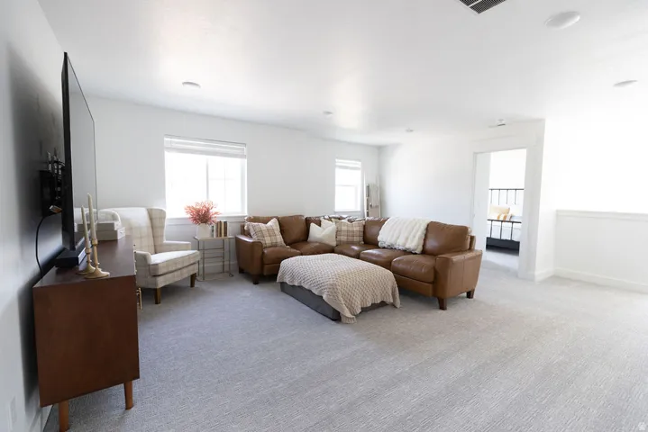 Spacious carpeted room featuring white walls and multiple windows