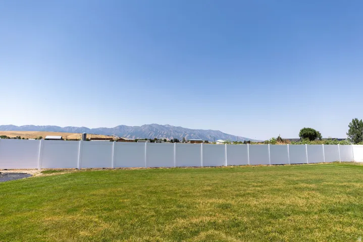 Expansive green lawn with a full-height perimeter fence, offering a mountain backdrop
